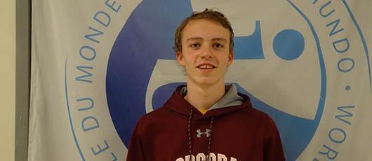 This is a photo of Corcoran student Connor Shanahan standing in front of a banner in his school foyer.