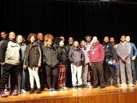 This is a photo of a group of student athletes and mentors standing together on stage.