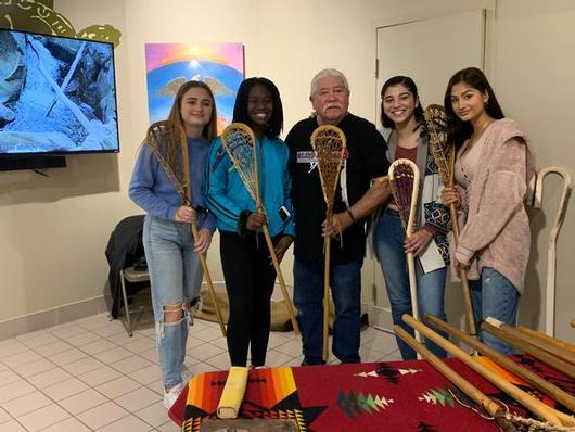 This is a photo of four Nottingham girls and a lacrosse stick maker, each holding a lacrosse stick.