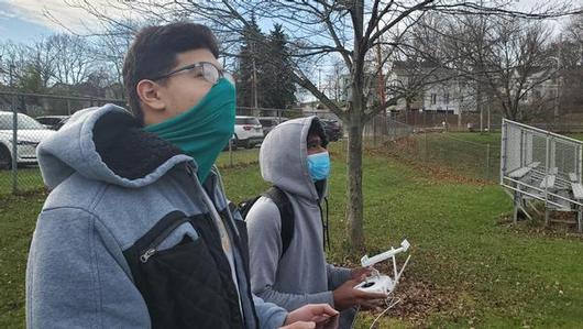 This is a photo of PSLA students Belal and Yohan, each looking to the sky while holding a drone controller.