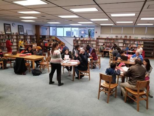 This is a photo of a school library with families gathered around tables for student-led conferences.