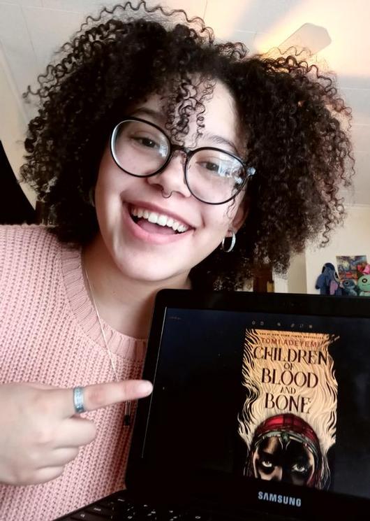ITC student Sammi McGiveron poses with the book she is reading in book club, 'Children of Blood and Bone.'